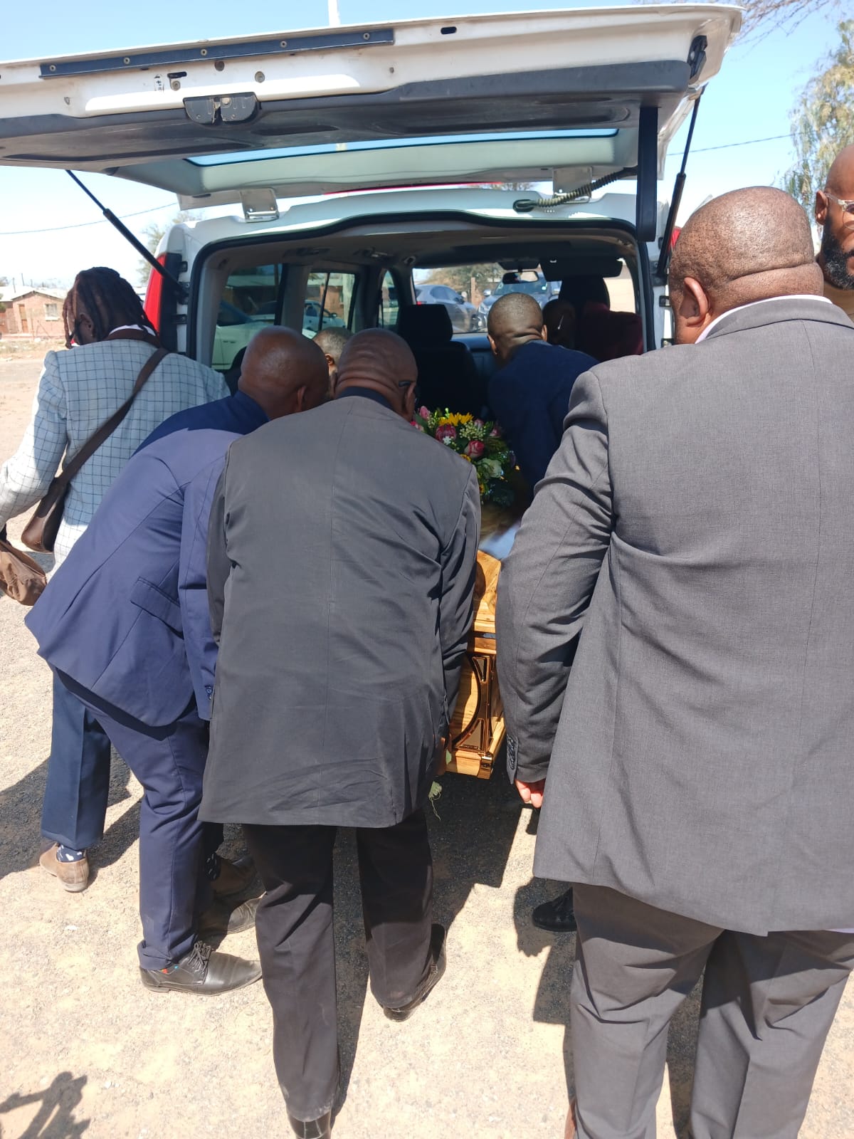 Pallbearers loading the casket into the funeral vehicle